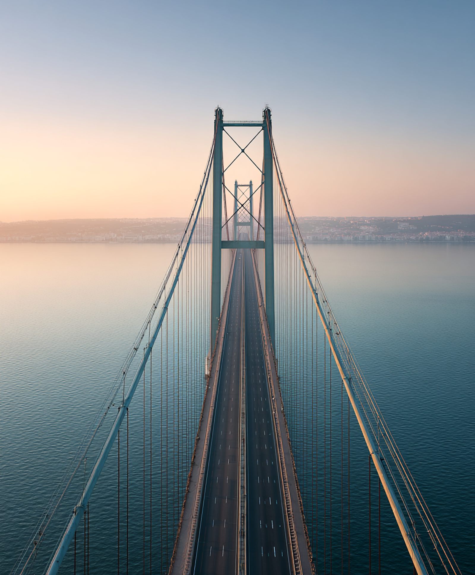 A suspension bridge stretching across water at dusk