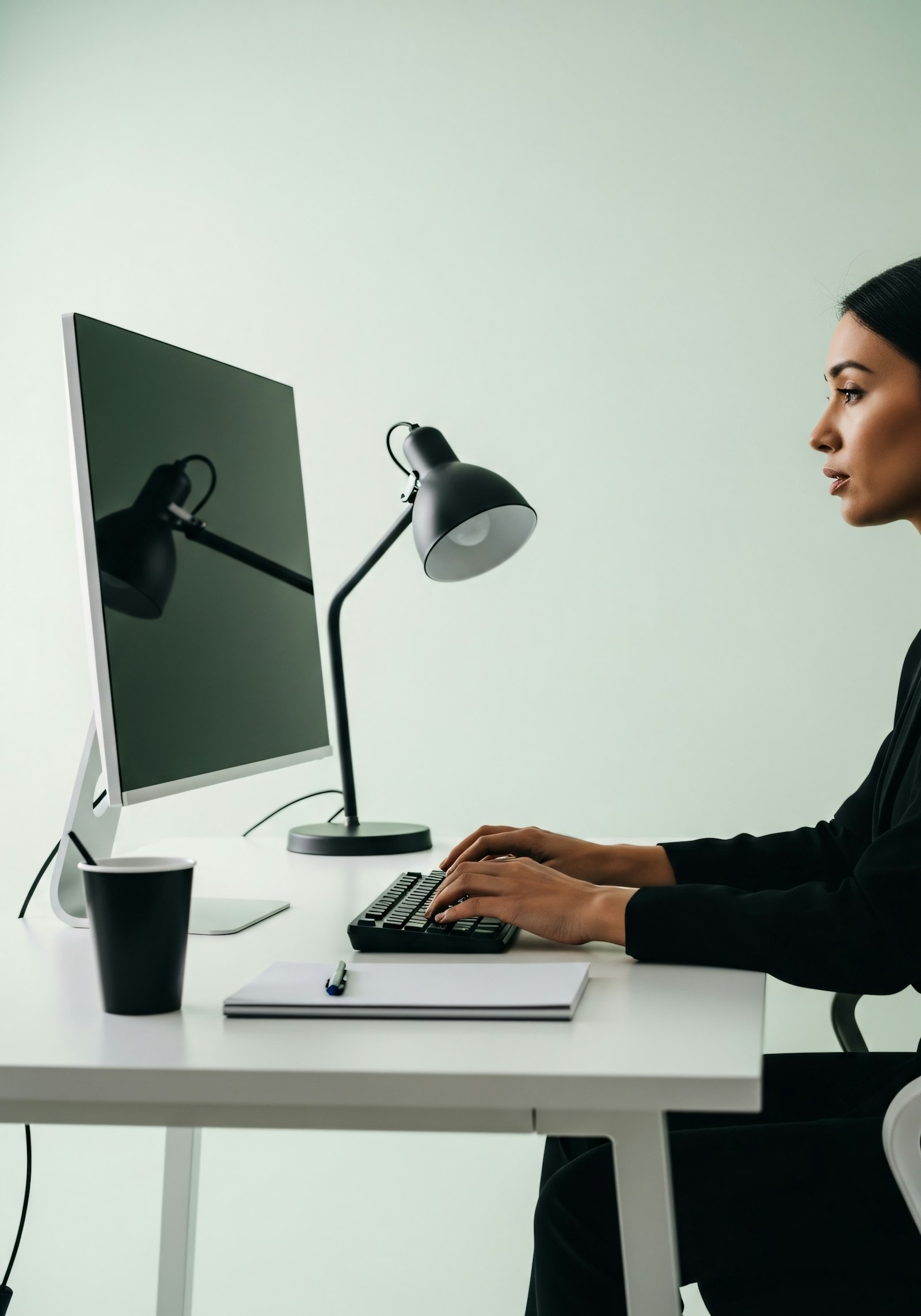 A person working at a clean desk with a large monitor