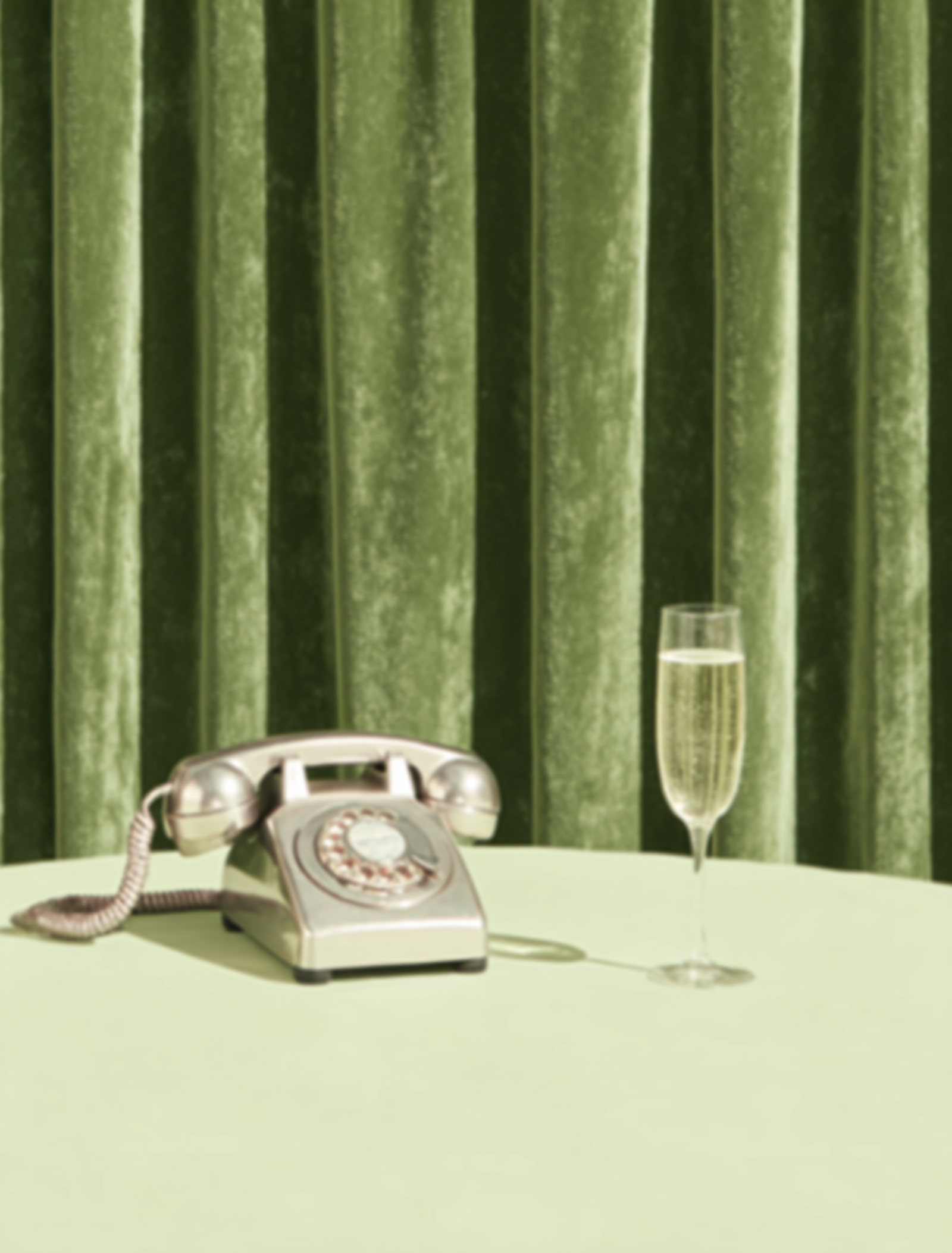 A vintage telephone on a table in front of green curtains